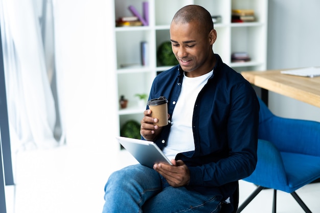 Feliz empresário afro-americano usando computador tablet.