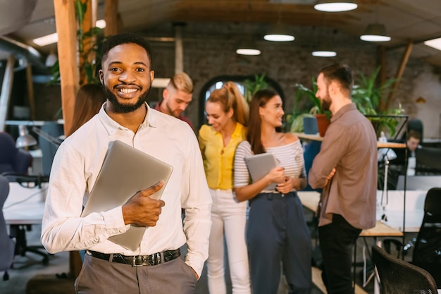 Feliz empresário com laptop sorrindo para a câmera