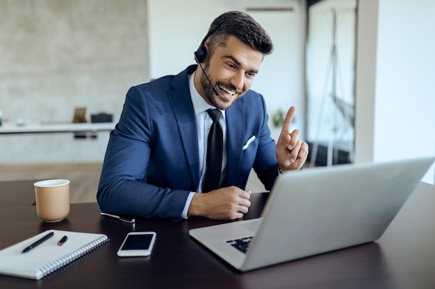 Feliz empresário conversando com alguém por videochamada enquanto trabalha no escritório