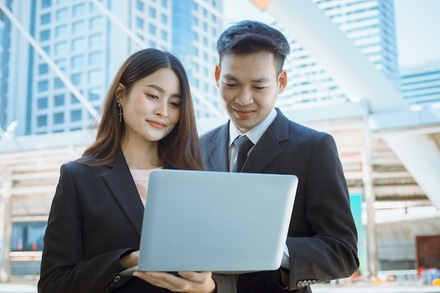 Feliz empresário e empresária mãos segurar laptop ao ar livre.