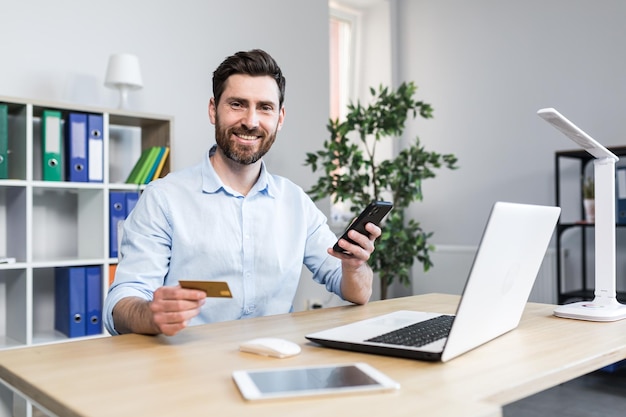 Feliz empresário faz compras online trabalhando no escritório marido tem cartão de crédito e usa laptop