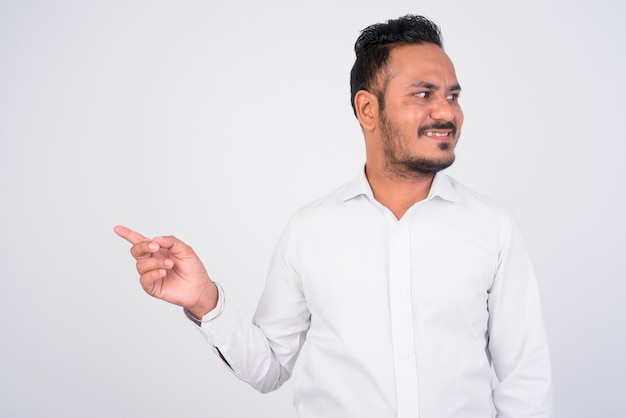 Feliz empresario indio barbudo que señala el dedo y mirando hacia el lado
