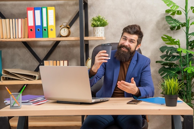 Foto feliz empresario maduro trabajando en una computadora con una taza de café en el negocio de la oficina