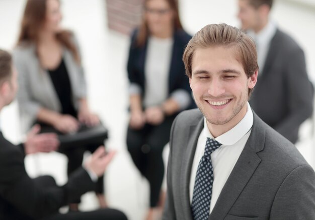 Feliz empresário posando na frente de sua equipe enquanto trabalhava em segundo plano