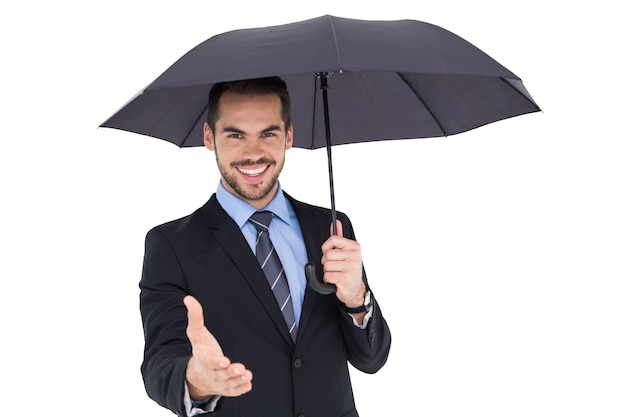 Feliz empresário sob um guarda-chuva que oferece aperto de mão