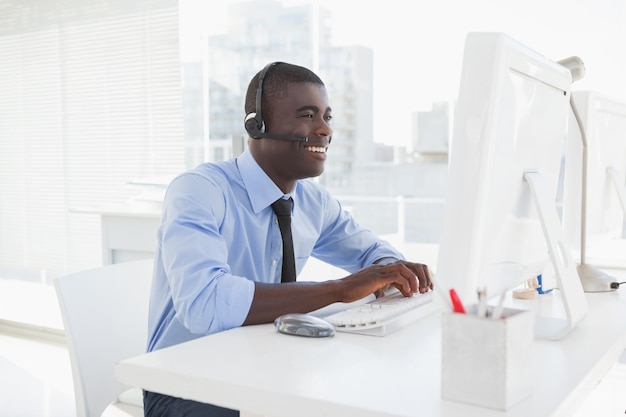 Feliz empresário trabalhando em sua mesa com fone de ouvido