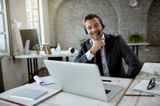 Feliz empresário usando computador e tendo reunião online enquanto trabalhava no escritório