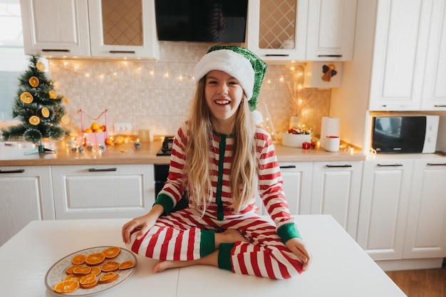 Feliz engraçada linda garota com chifres, sentado em uma cozinha aconchegante em casa. decoração de natal