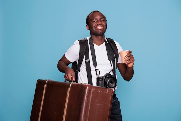 Feliz entusiasta da fotografia com bagagem e câmera DSLR se preparando para a partida da viagem de férias. Fotógrafo americano africano com bagagem, mochila e dispositivo fotográfico pronto para o citybreak.