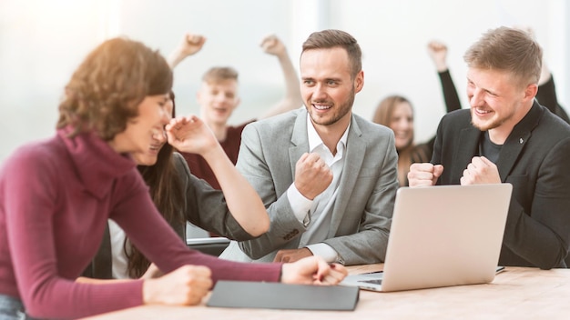 Feliz equipo de empleados sentados en el escritorio de la oficina