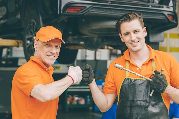 El feliz equipo de servicio mecánico de automóviles disfruta trabajando juntos en el garaje