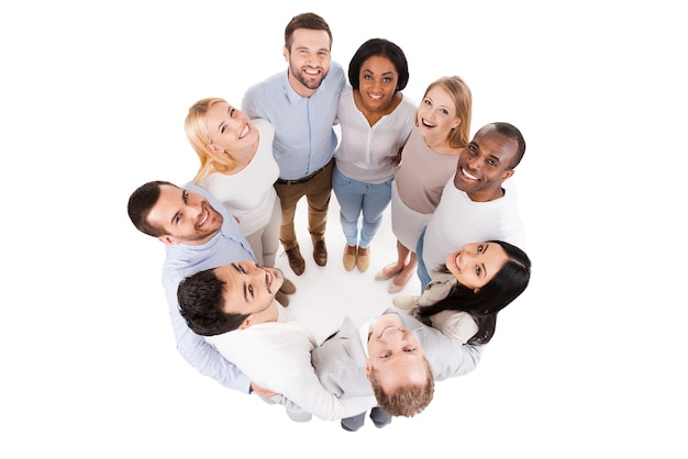 Foto feliz equipo unido. vista superior del grupo diverso positivo de personas felices en ropa casual elegante que se unen entre sí y de pie en círculo