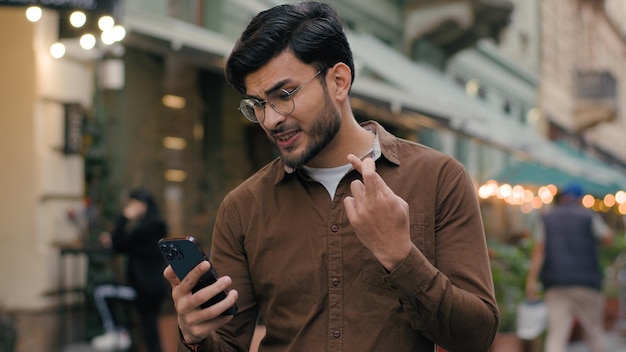 Foto feliz esperançoso sortudo indiano árabe homem étnico homem homem de negócios homem jovem estudante segurar telefone móvel