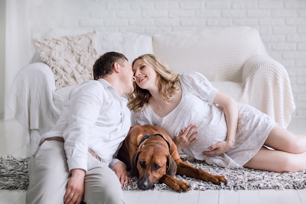 Feliz esposo y esposa embarazada sentada en la cama