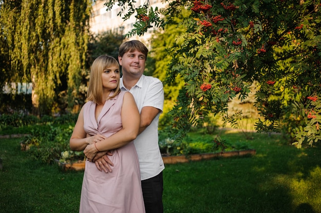 Foto feliz esposo y esposa de pie en el parque verde bajo las ramas de los árboles