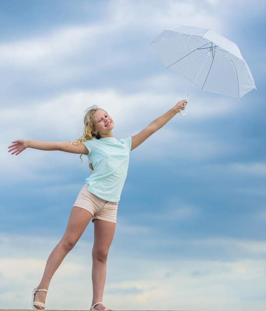 Feliz de estar cerca de una niña feliz con un paraguas de buen humor en cualquier clima escolar temporada de otoño pronóstico del tiempo lluvioso otoño niño moda niño en el cielo nublado protección contra la lluvia