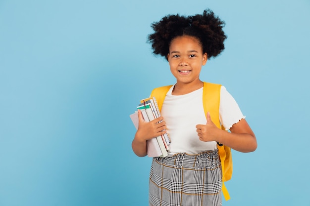 Foto feliz estudante afro-americana apontando legal em fundo azul de volta ao conceito da escola