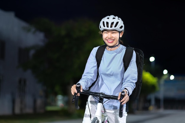 Feliz estudante asiática andando de bicicleta como atleta depois do trabalho da universidade da escola de escritório