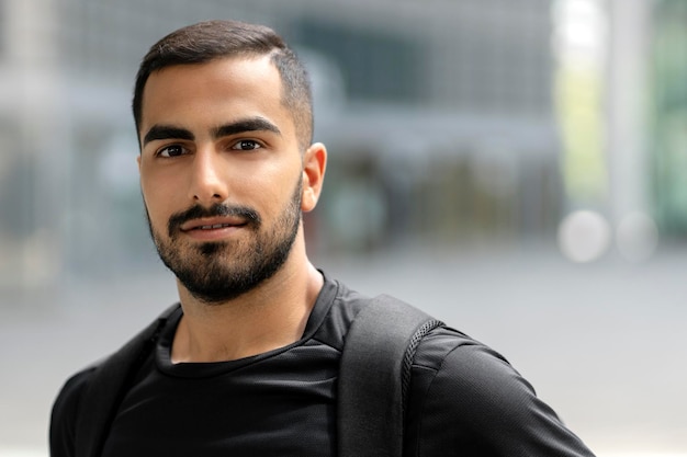 Feliz estudante barbudo bonito olhando para a câmera e sorrindo