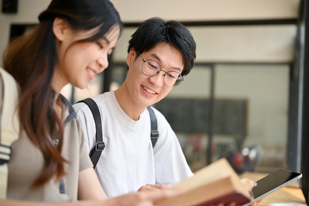 Feliz estudante universitário asiático ensinando história para sua namorada em um café no fim de semana