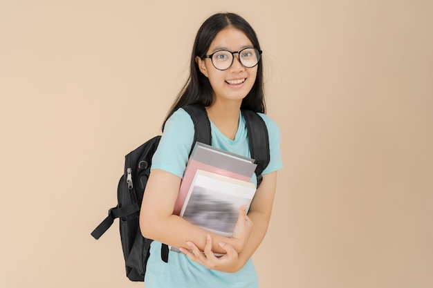 Una feliz estudiante asiática usa anteojos y lleva un libro