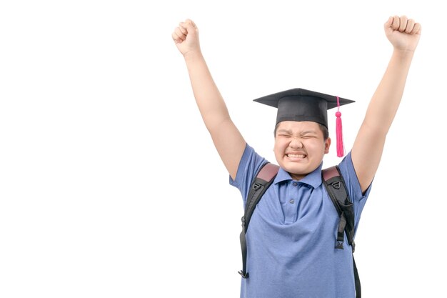 Feliz estudiante asiático usa gorro de graduación y levanta la mano aislada en blanco