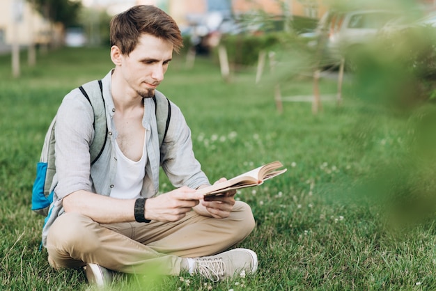 Feliz estudiante masculino celebración de un libro y la lectura