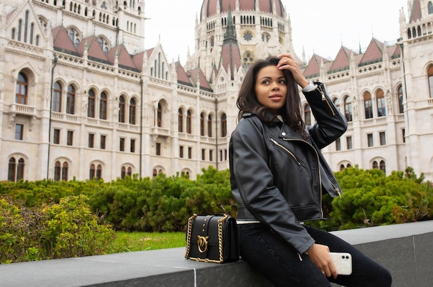 Feliz estudiante negra disfrutando de una gran vista del edificio del Parlamento en la ciudad de Budapest.