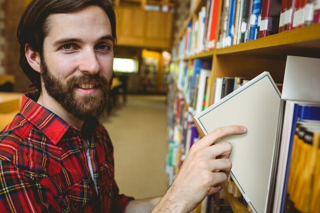 Feliz estudiante recogiendo libros en la biblioteca