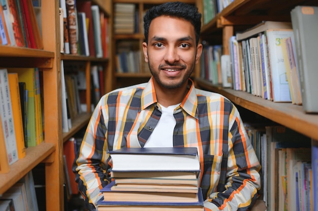 Feliz estudiante universitario masculino de raza mixta indio o árabe inteligente en la biblioteca