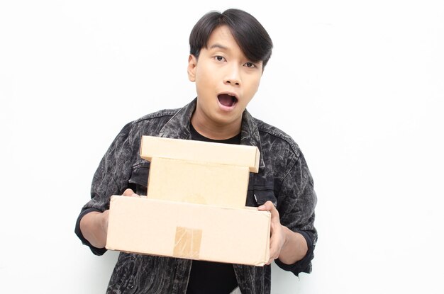 Feliz extasiado joven asiático sosteniendo paquete paquete caja aislado sobre fondo blanco.
