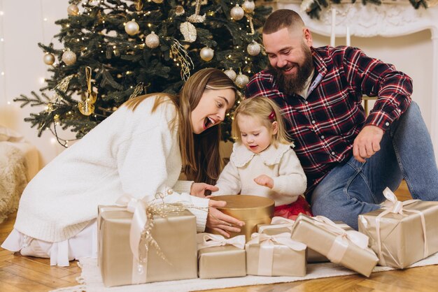 Feliz família abrindo presentes de Natal perto da árvore de Natal decorada