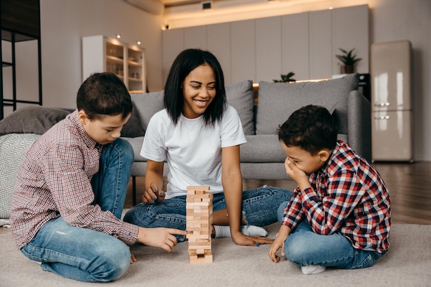 Feliz família afro-americana sentada no chão e jogando jenga