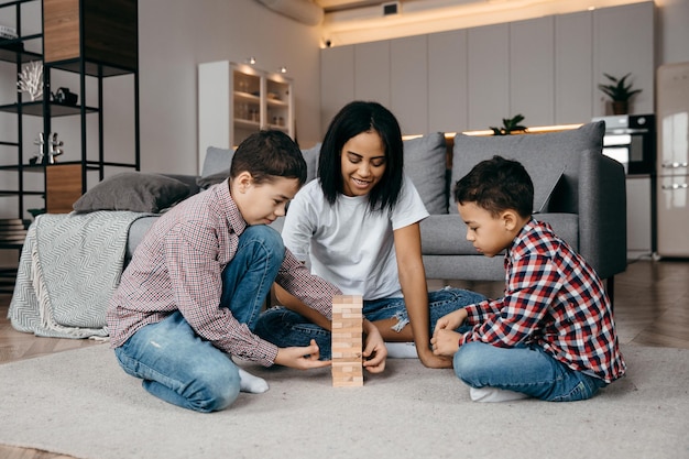 Feliz família afro-americana sentada no chão e jogando jenga