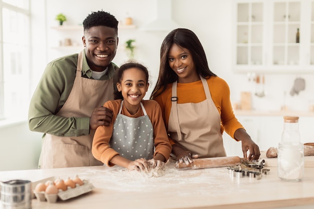 Feliz familia afroamericana horneando masa amasadora en la cocina