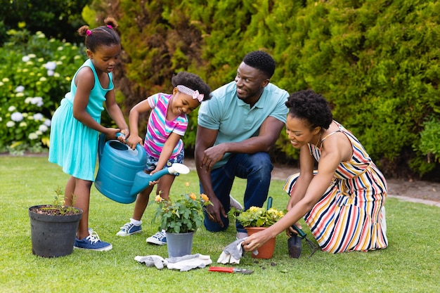 Feliz familia afroamericana regando plantas juntas en el jardín