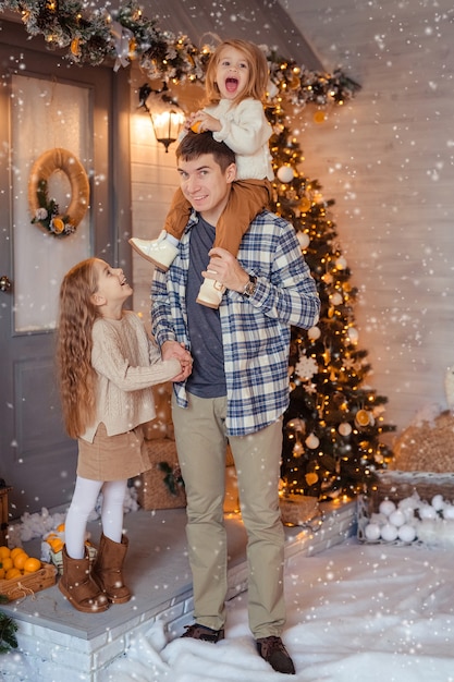 Feliz familia alegre esperando el año nuevo en la calle con el telón de fondo de una casa de madera