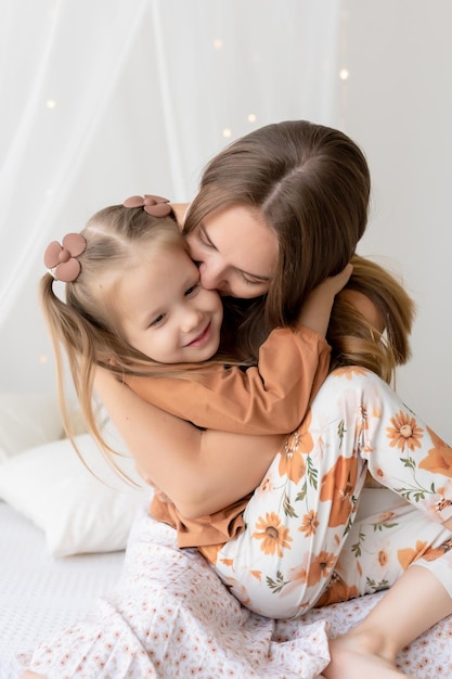 Feliz família amorosa Mãe e sua filha menina brincam e se divertem na cama no quarto O prazer de ser mãe o dia das mães cumprimenta o conceito de um doce momento juntos