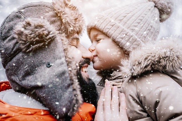 Feliz família amorosa Pai e seu bebê estão brincando e se abraçando ao ar livre Criança bonitinha e papai no inverno nevado caminham na natureza Conceito de inverno gelado