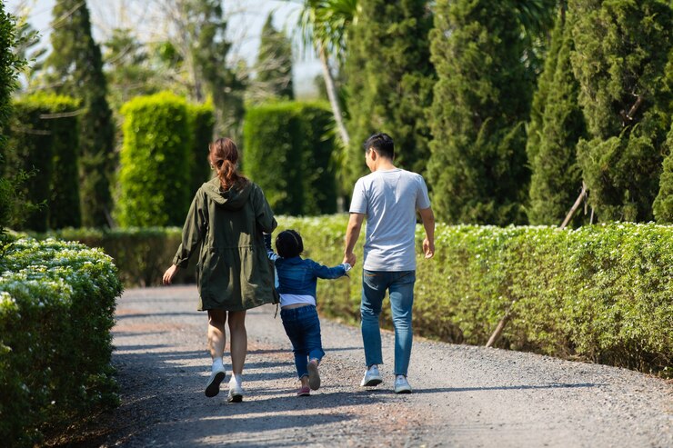 Feliz familia asiática caminando y tomados de la mano junto con los niños en el parque. Feliz, familia, padre, madre e hija, niño