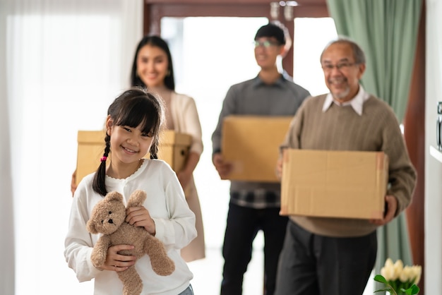 Feliz família asiática de várias gerações segurando uma caixa de papelão e se mudando para uma nova casa