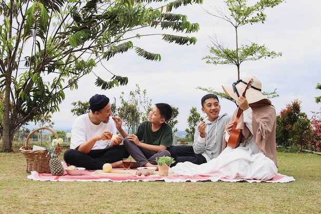 Feliz família asiática fazendo piquenique no parque num dia ensolarado de verão