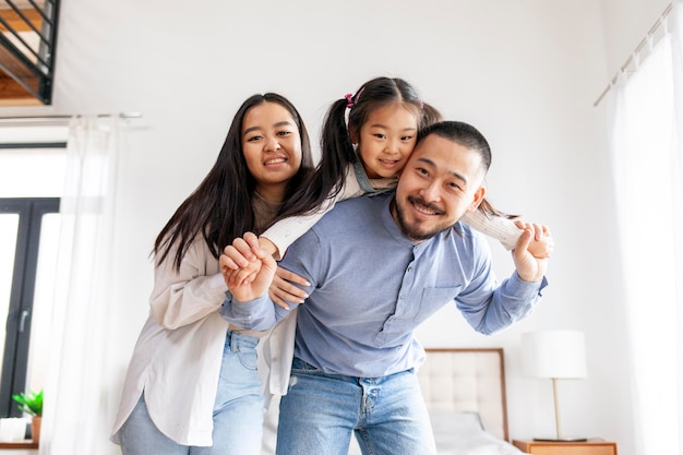 feliz familia asiática con una hija pequeña de pie en casa y regocijarse mamá y papá sostener el niño