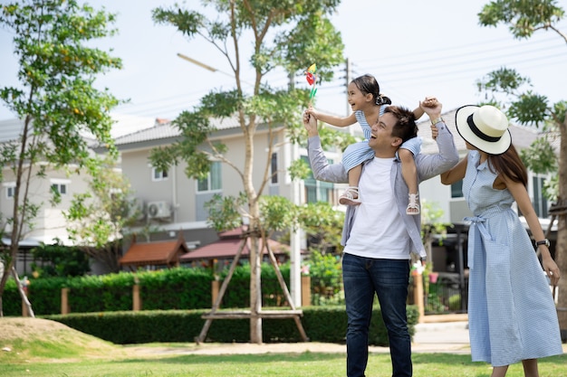 Feliz familia asiática. Padre le dio a su hija a cuestas en un parque a la luz natural del sol y en casa. Concepto de vacaciones familiares