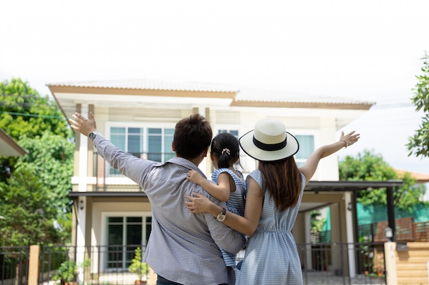 Feliz familia asiática. Padre, madre e hija cerca de casa nueva. Bienes raíces