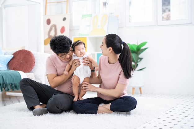 Feliz familia asiática sentada en el dormitorio de los niños en casa