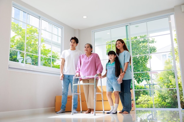 Feliz familia asiática siente emoción al mudarse a una nueva casa Abuela usando un padre andador