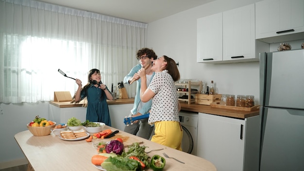 Foto feliz familia bailando mientras la madre toca el ukulele y se mueve a la música pedagogía