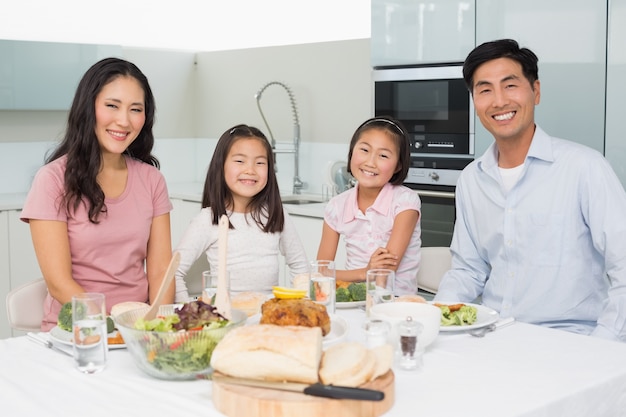 Feliz familia de cuatro disfrutando de comida saludable en la cocina