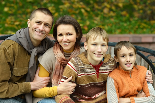 Feliz familia de cuatro parados juntos en el parque en otoño